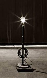 A lit bare bulb ghost lamp on a stage